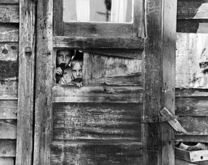 image of children looking through a wooden door