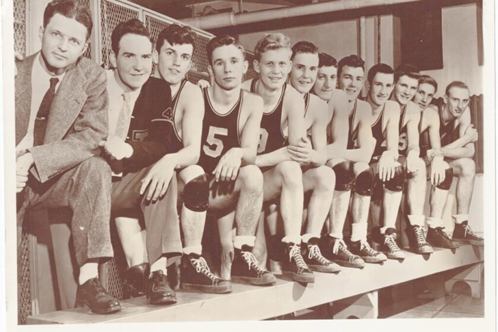 Old photo of a high school basketball team sat on a wall