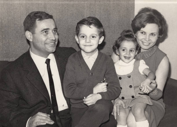 Vintage image from the the 60s: Smiling mature couple posing with their children sitting in their living room couch