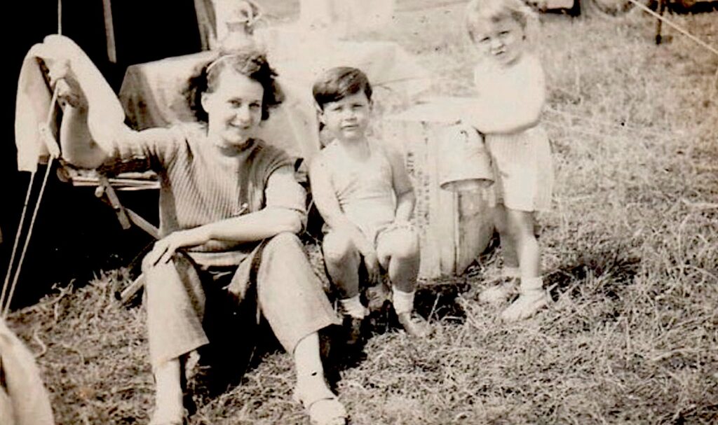 Mother and two younger children sat on the grass.